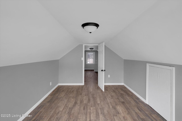 additional living space with baseboards, lofted ceiling, and wood finished floors