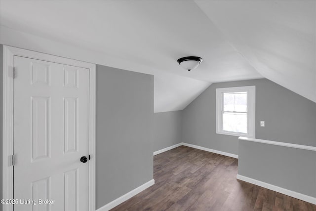 additional living space with dark wood finished floors, vaulted ceiling, and baseboards