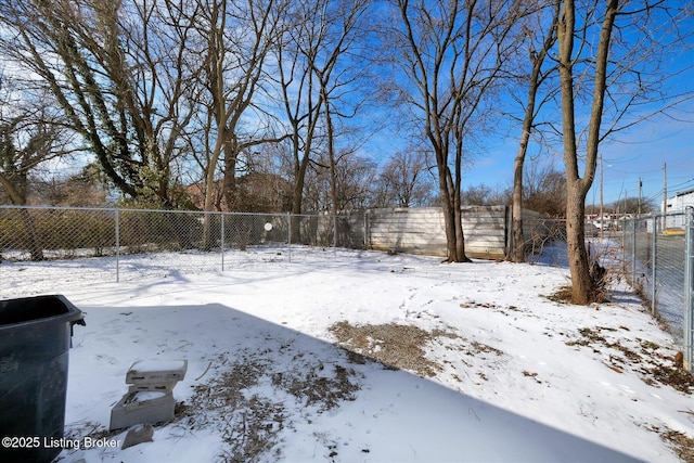 snowy yard with a fenced backyard