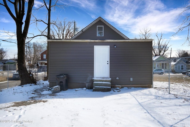 snow covered back of property with entry steps and fence