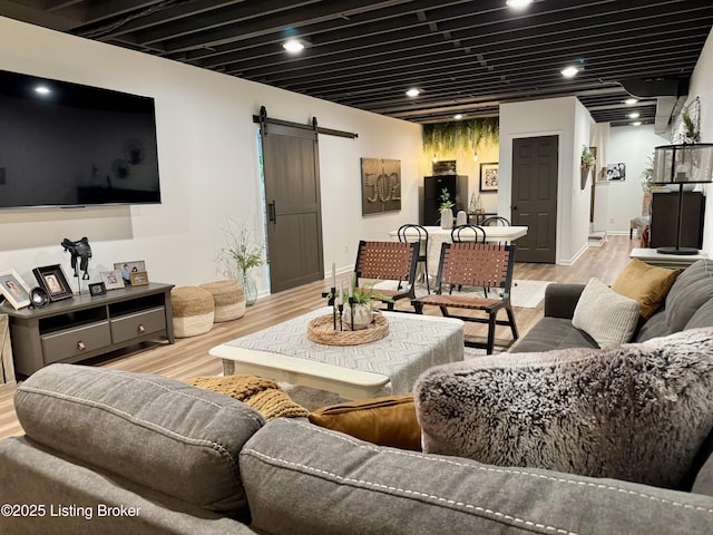 living room featuring a barn door, light wood-style flooring, and baseboards