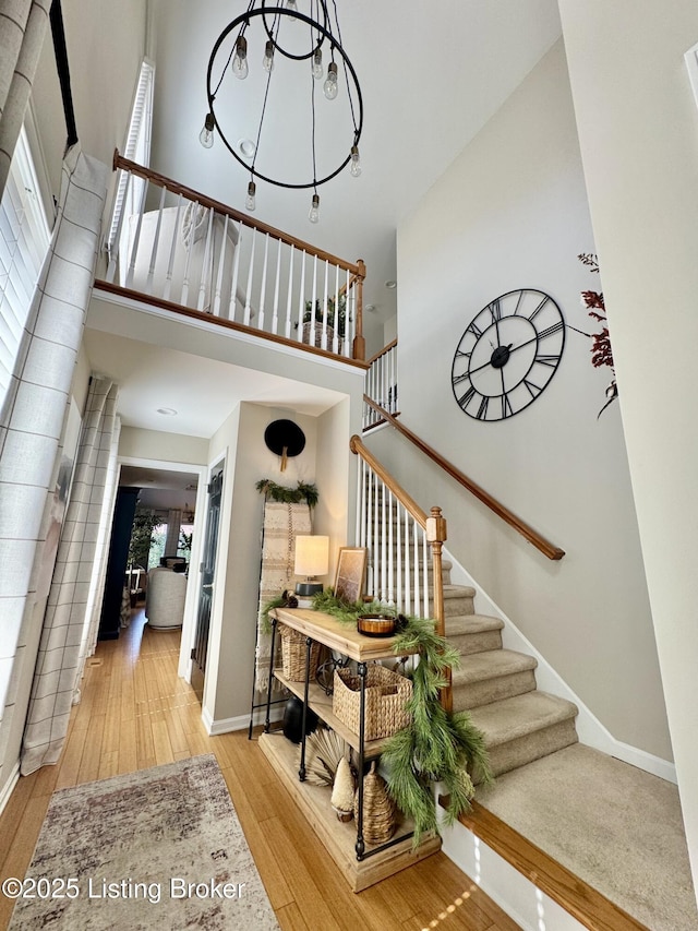 staircase with baseboards, wood-type flooring, and a towering ceiling