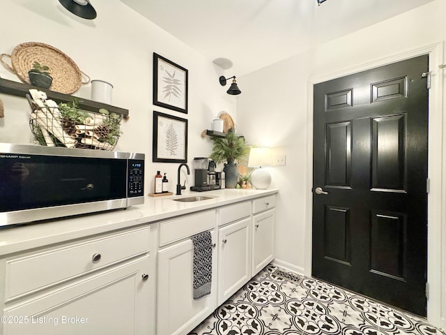 bar featuring a sink, stainless steel microwave, baseboards, and light tile patterned flooring