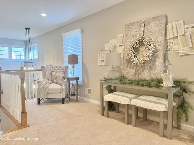 living area featuring visible vents, baseboards, an upstairs landing, and carpet flooring