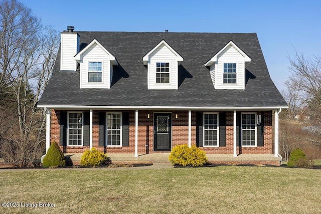 new england style home featuring a front yard, covered porch, and brick siding