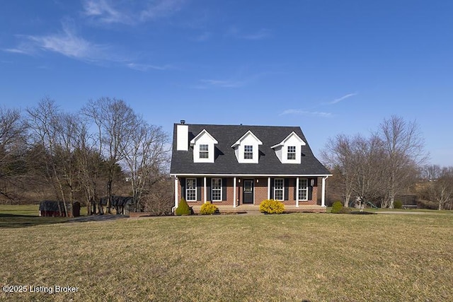 cape cod house featuring brick siding and a front yard