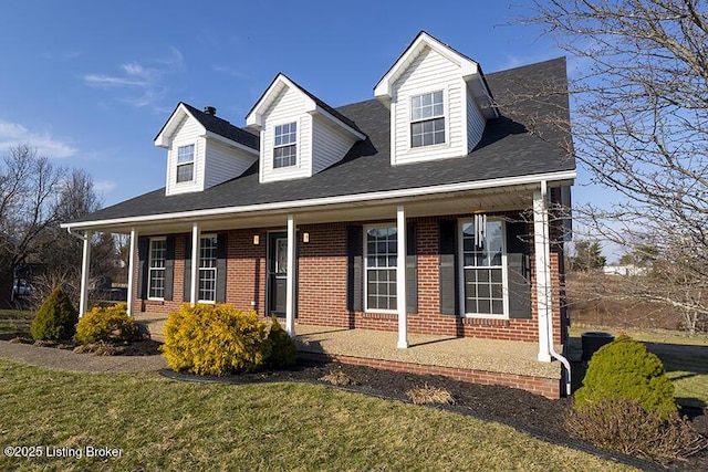 cape cod-style house featuring brick siding, a porch, and a front lawn