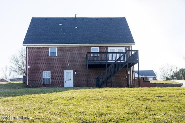 rear view of property featuring brick siding, a wooden deck, a lawn, and stairs