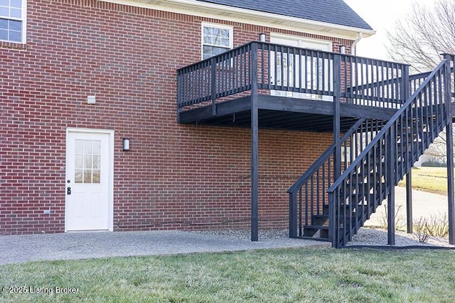 exterior space featuring stairs, brick siding, roof with shingles, and a wooden deck