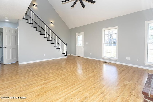 unfurnished living room with stairs, light wood-style flooring, and plenty of natural light