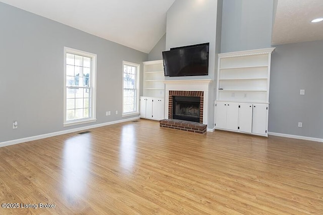 unfurnished living room featuring light wood-style flooring, a brick fireplace, and baseboards