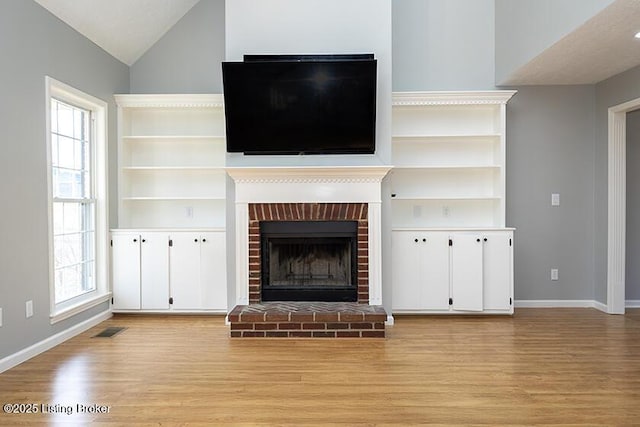 unfurnished living room featuring visible vents, baseboards, a fireplace, and light wood finished floors