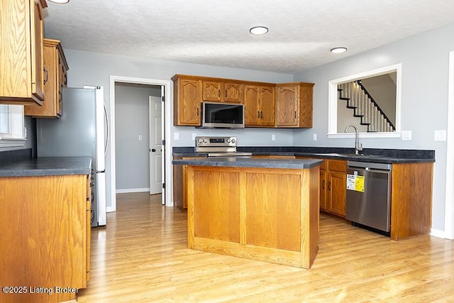 kitchen with dark countertops, light wood finished floors, and appliances with stainless steel finishes