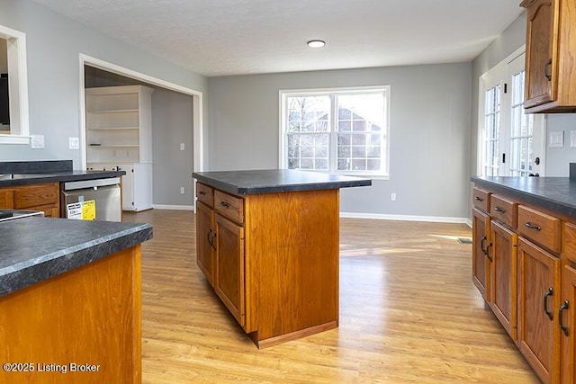 kitchen featuring light wood-style floors, brown cabinets, dark countertops, and dishwasher