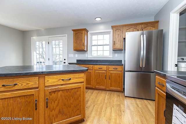 kitchen with dark countertops, brown cabinets, stainless steel appliances, and light wood-style floors