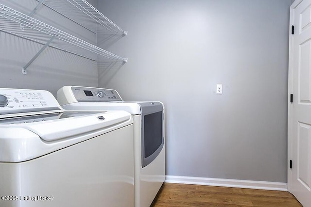 clothes washing area featuring washer and dryer, baseboards, wood finished floors, and laundry area