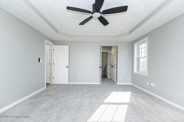 unfurnished bedroom featuring carpet flooring, a raised ceiling, and baseboards