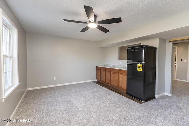 kitchen with plenty of natural light, brown cabinets, light colored carpet, and freestanding refrigerator