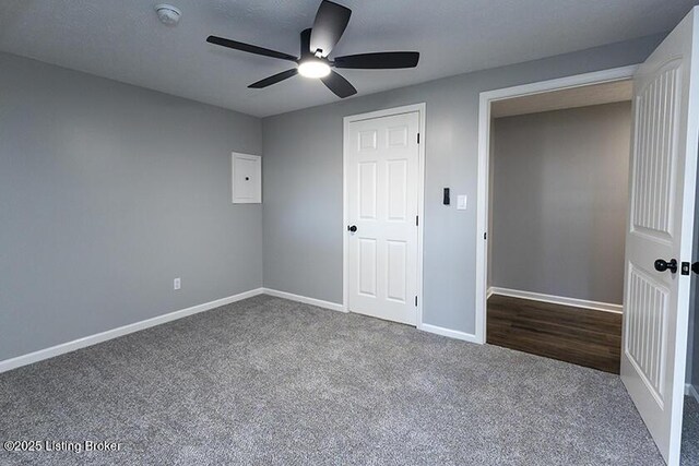 unfurnished bedroom with baseboards, dark carpet, and ceiling fan