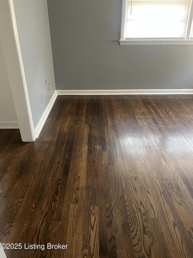 empty room featuring dark wood-style floors and baseboards