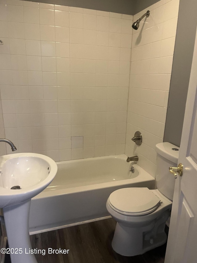 bathroom featuring bathing tub / shower combination, toilet, and wood finished floors