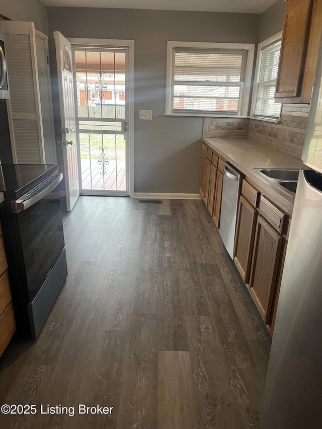 kitchen featuring a wealth of natural light, backsplash, dishwasher, and dark wood-style flooring