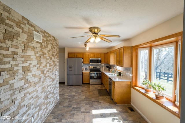 kitchen with visible vents, a sink, light countertops, appliances with stainless steel finishes, and stone finish flooring