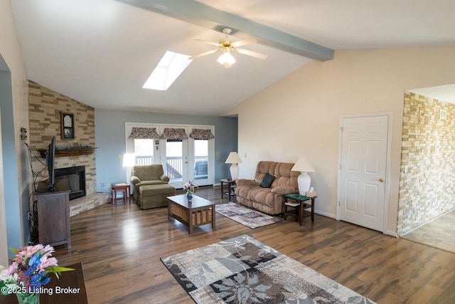 living area with vaulted ceiling with skylight, a stone fireplace, and dark wood finished floors