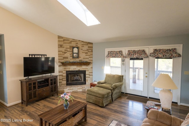 living area with lofted ceiling with skylight, wood finished floors, a fireplace, and baseboards