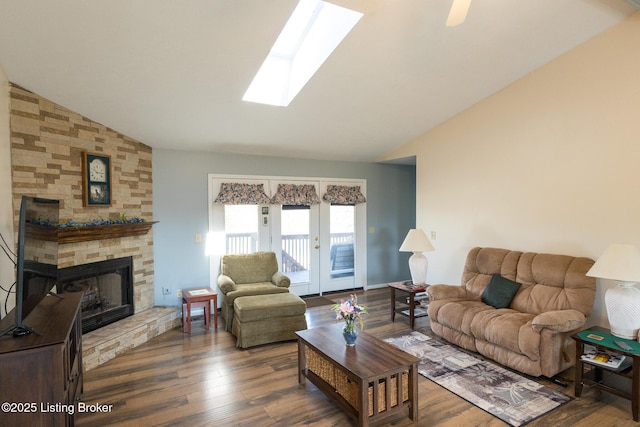 living area with vaulted ceiling with skylight, a fireplace, and wood finished floors