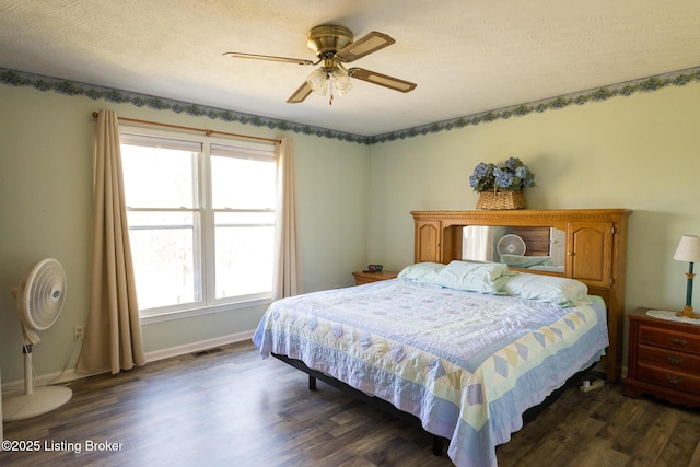 bedroom with visible vents, baseboards, dark wood finished floors, and a ceiling fan