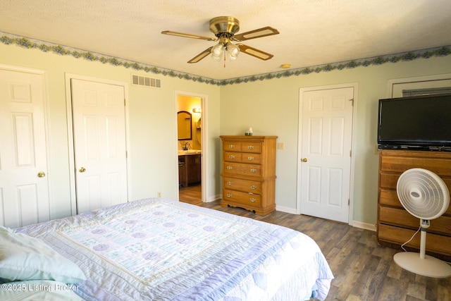 bedroom featuring visible vents, connected bathroom, dark wood-type flooring, and baseboards