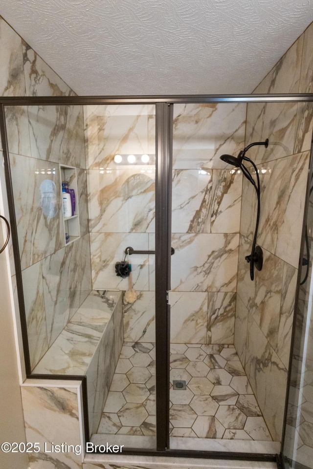 bathroom with a marble finish shower and a textured ceiling