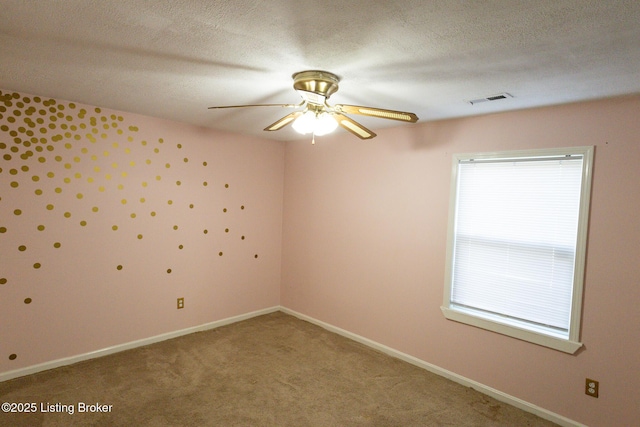 carpeted spare room with visible vents, a textured ceiling, baseboards, and a ceiling fan