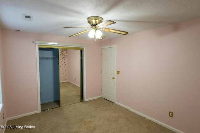 unfurnished bedroom with baseboards, ceiling fan, a closet, a textured ceiling, and carpet flooring