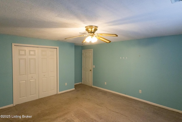 unfurnished bedroom featuring a closet, carpet flooring, a textured ceiling, and baseboards