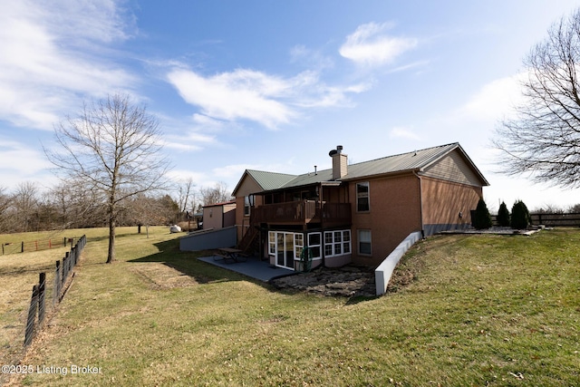 back of house with a lawn, a deck, fence, brick siding, and a chimney