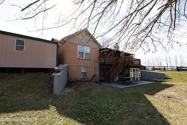 rear view of house featuring brick siding, fence, stairway, a yard, and a patio area