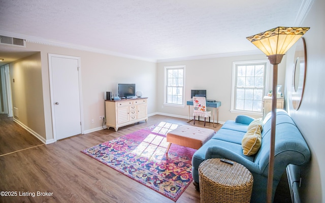 living room featuring wood finished floors, visible vents, and ornamental molding