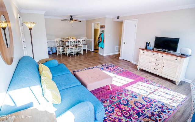 living area featuring visible vents, ornamental molding, ceiling fan, and wood finished floors