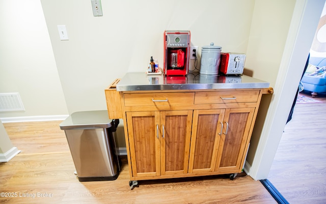 bar with visible vents, light wood-type flooring, and baseboards