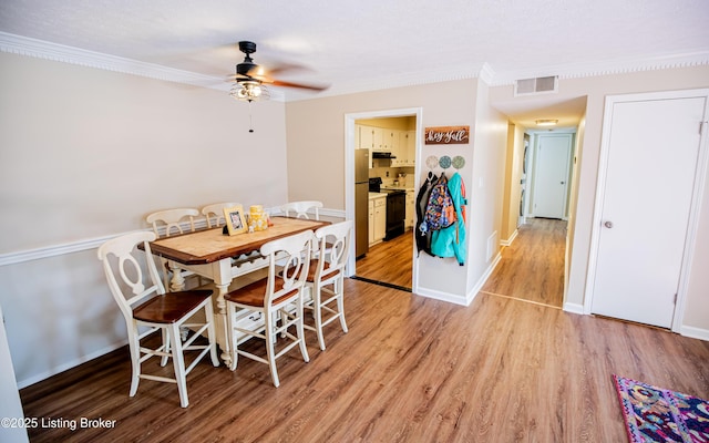 dining space with visible vents, crown molding, baseboards, light wood-style floors, and a ceiling fan