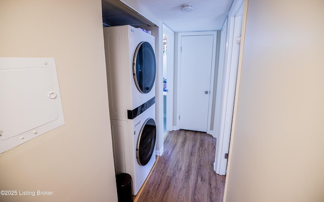 laundry area featuring stacked washer and dryer, wood finished floors, and laundry area