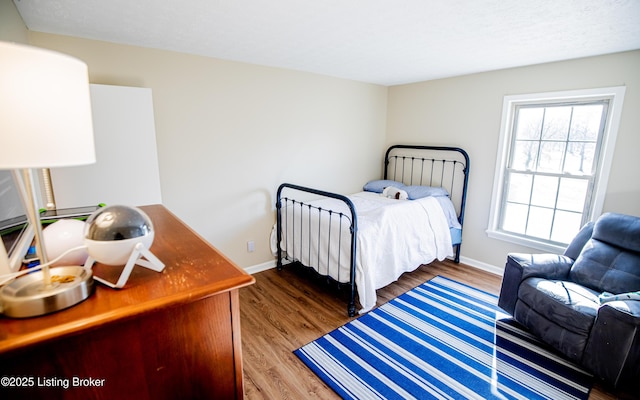 bedroom with baseboards, a textured ceiling, and wood finished floors