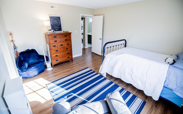 bedroom with visible vents, baseboards, and wood finished floors