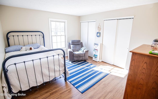 bedroom featuring two closets and wood finished floors