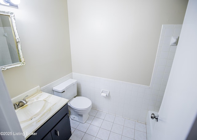 bathroom featuring a wainscoted wall, toilet, tile walls, tile patterned flooring, and vanity