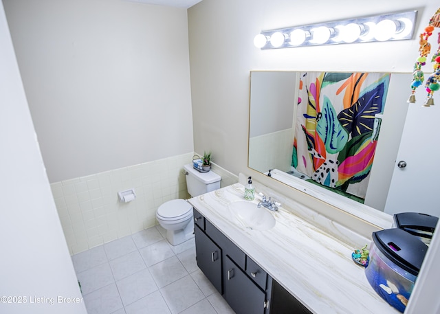 full bathroom featuring a wainscoted wall, toilet, tile walls, tile patterned flooring, and vanity