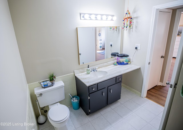 bathroom with vanity, a wainscoted wall, tile patterned flooring, tile walls, and toilet