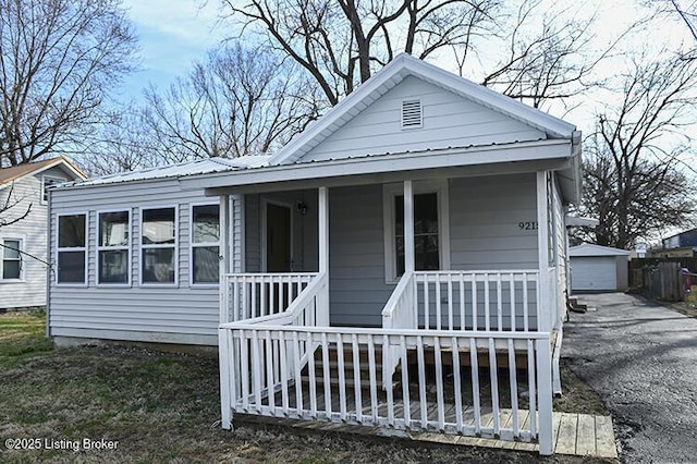 view of front facade featuring metal roof, an outbuilding, and a porch